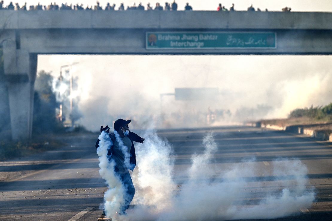 A Tehreek-e-Insaf (PTI) party's supporter attempts to throw back tear gas shells fired by riot policemen in Hasan Abdal, Punjab province, Pakistan, on November 25.